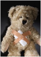 Ein traurig schauender Teddybär mit Pflastern auf dem Bauch